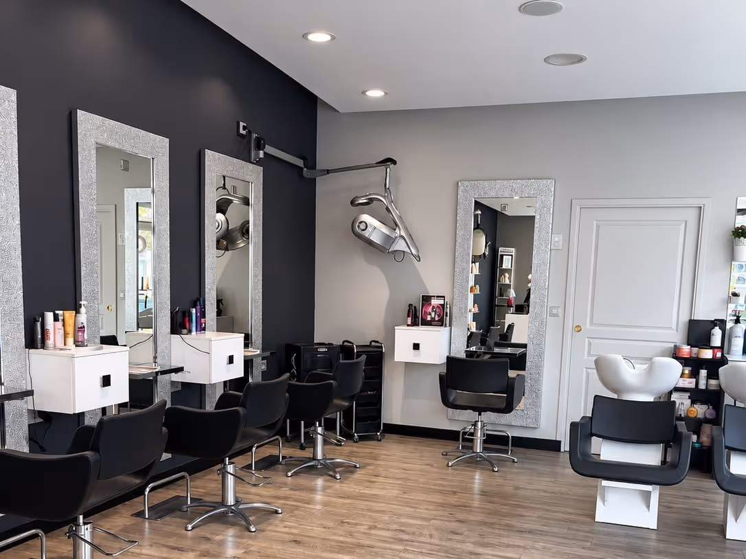 Le salon Cheveux d'Ange : mur anthracite, miroirs à cadre argenté et fauteuils noirs sur parquet